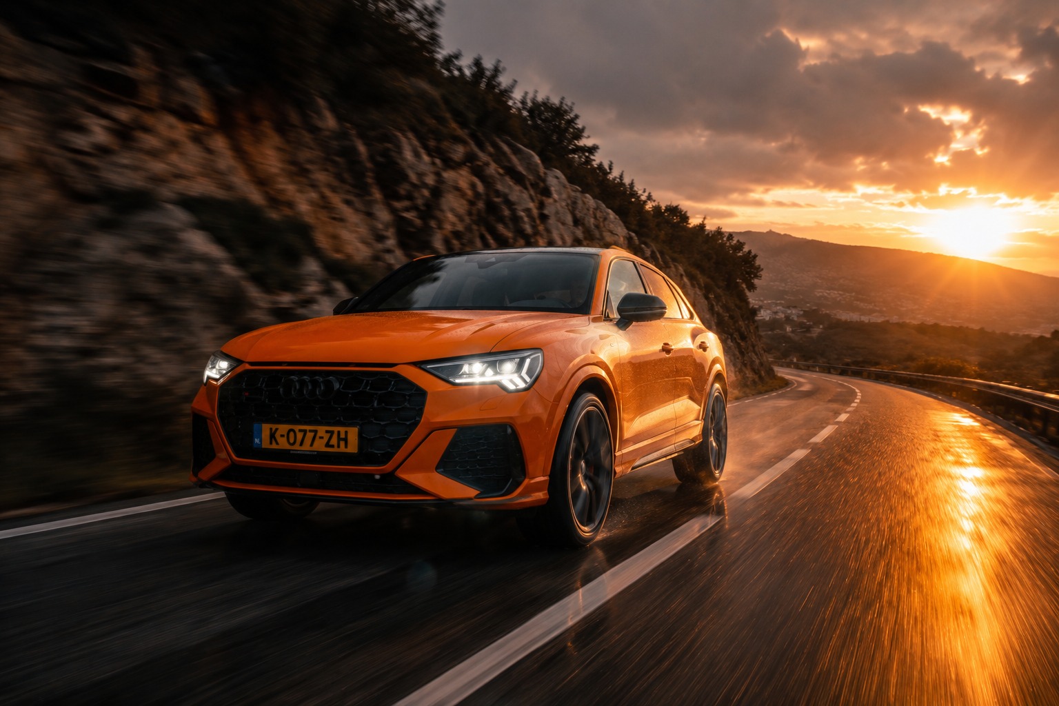 Oranje leaseauto rijdt over een bergweg bij zonsondergang